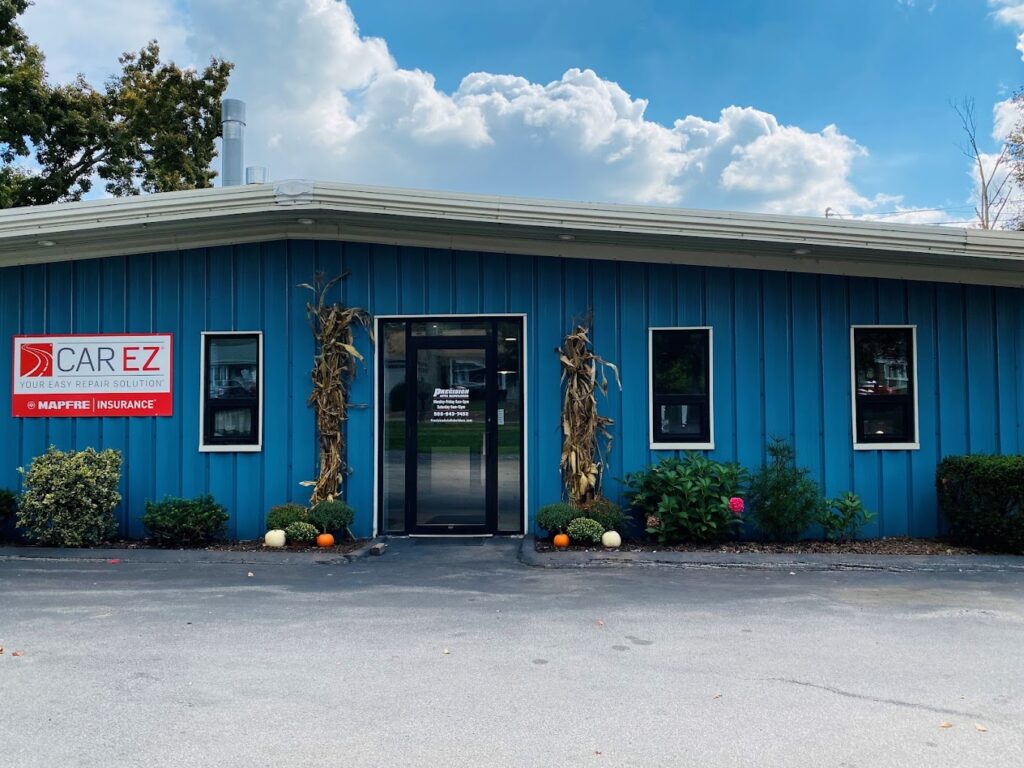 A bright blue building with a Carez insurance logo, surrounded by trees and a paved parking area with pumpkins and other fall decorations.